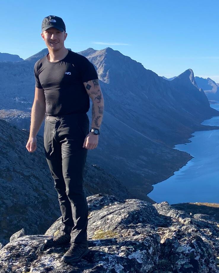 Hugo, trainer bij Trainingsloods Ede, op een bergtop boven een fjord