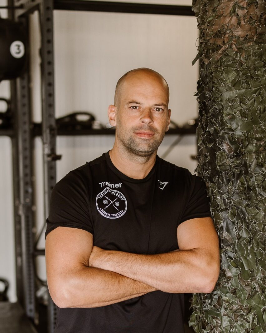 Ruben, trainer bij Trainingsloods Ede, met gekruiste armen in de loods aan de Bospoort